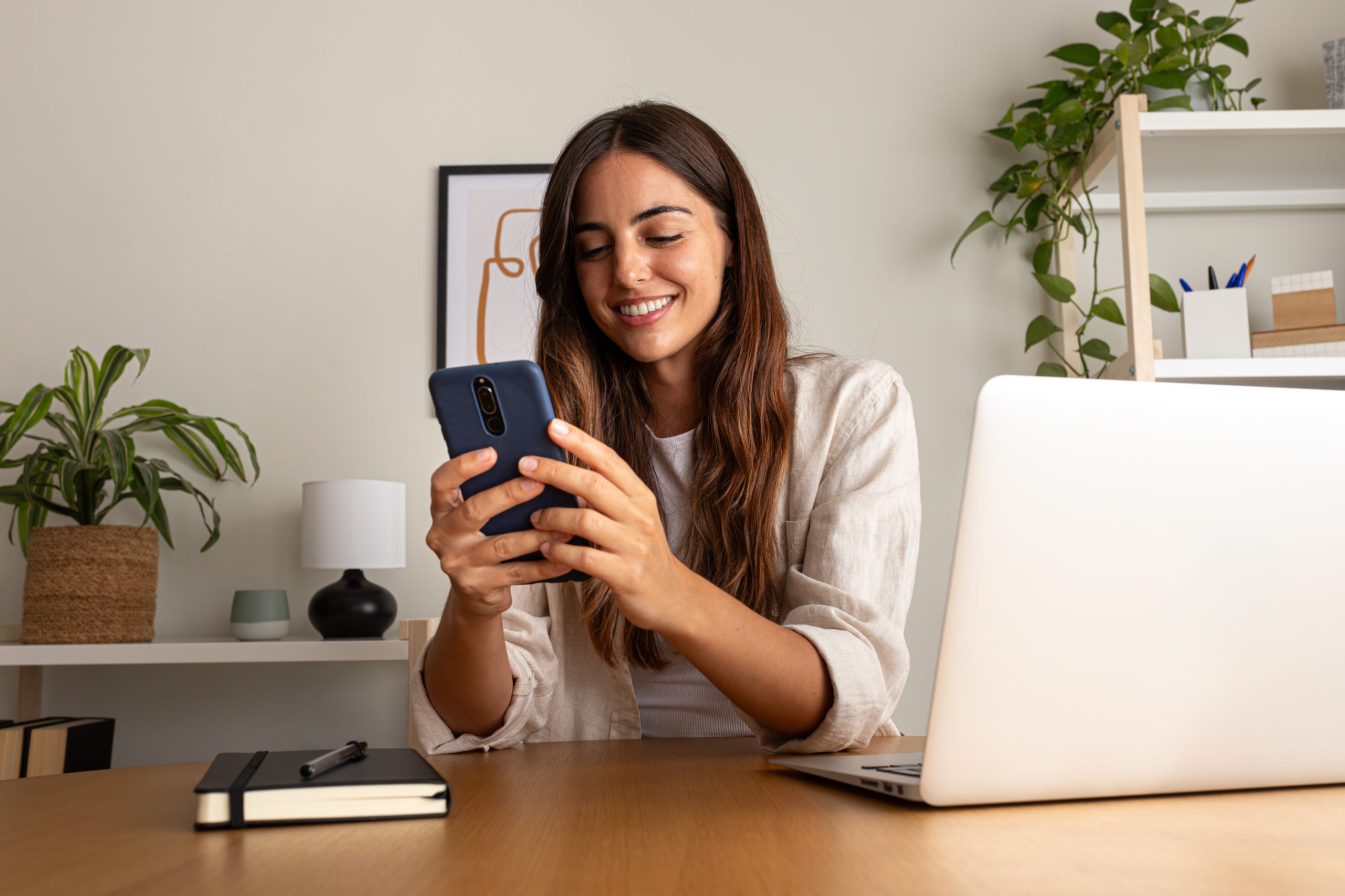 Young woman working using mobile phone working at home.
