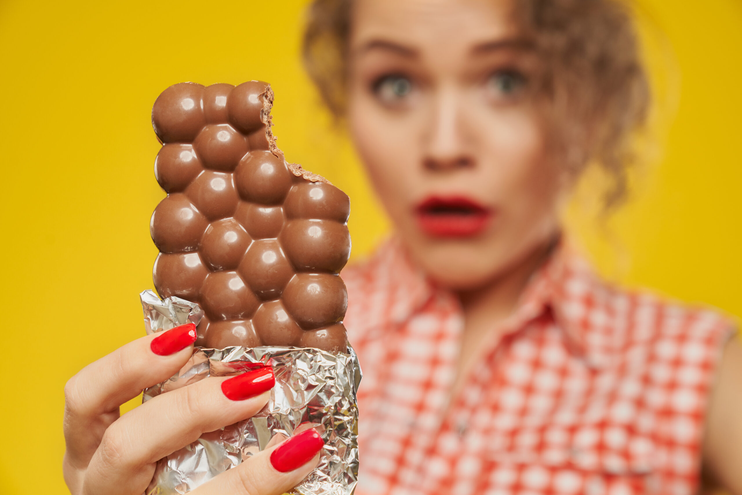 Milk porous chocolate bar in hand of girl with red nails.